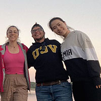 Three students stand arm in arm, one wearing a VCU sweatshirt